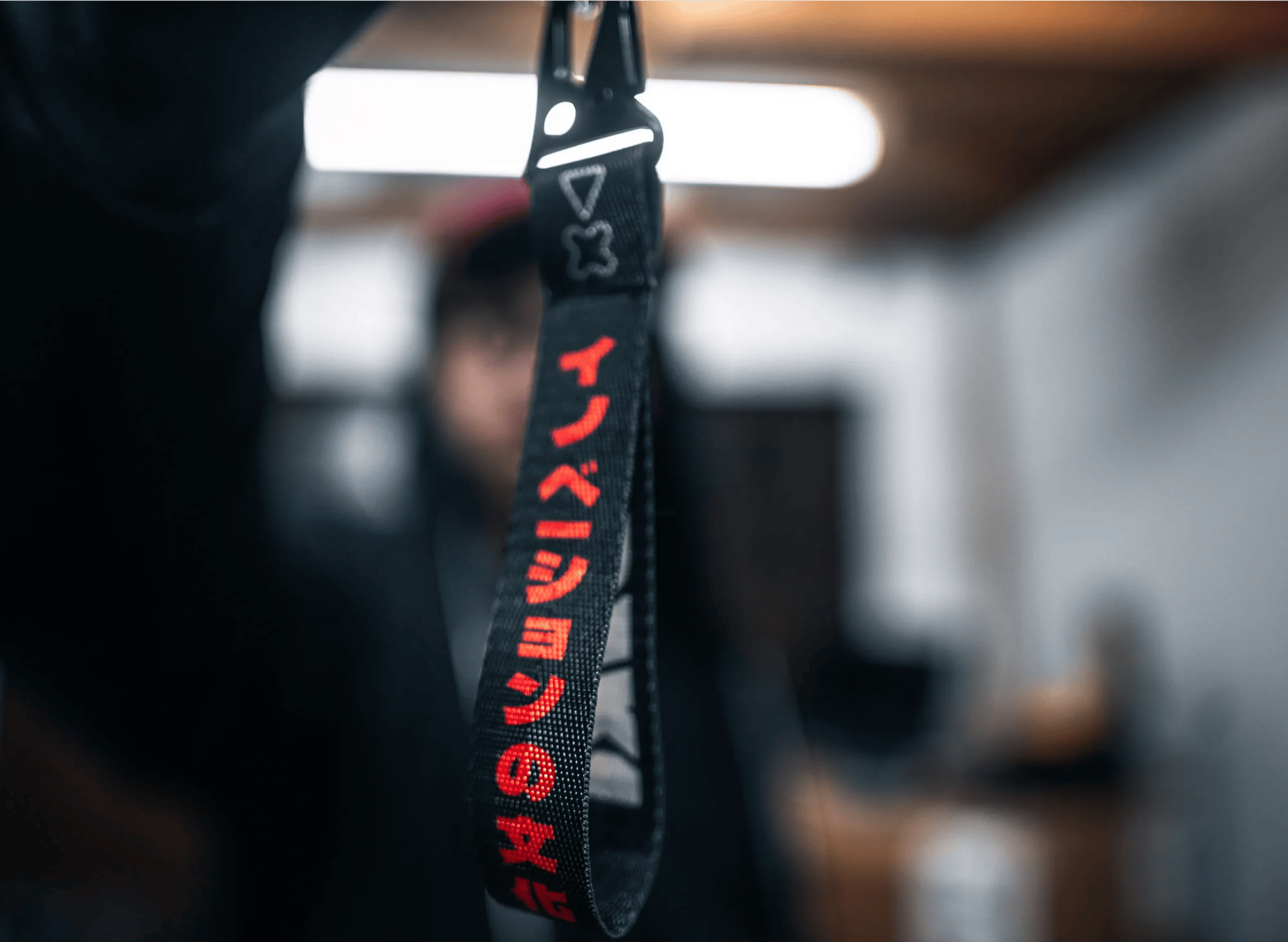 A closeup photograph of an Adaki key chain being held up to the camera, the background heavily out of focus